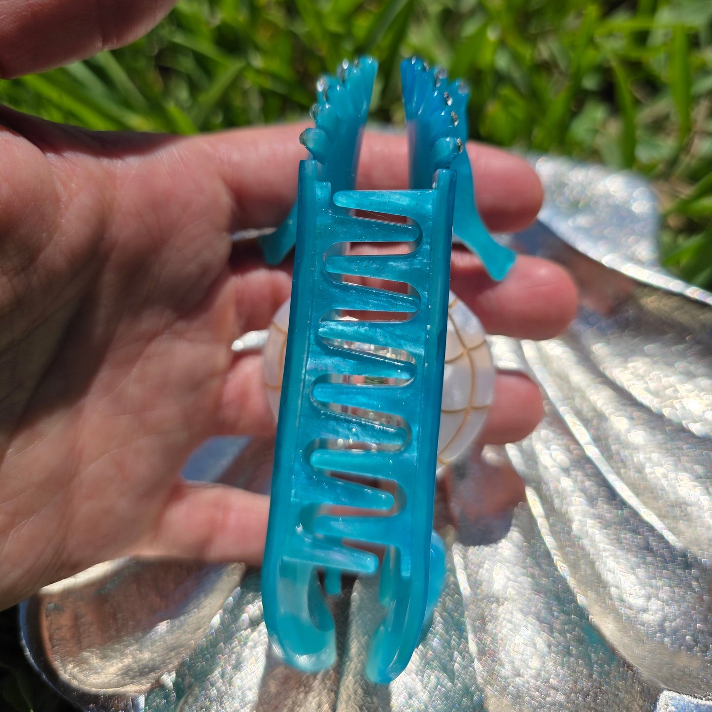 Blue hair clip held in a hand view of side 